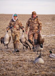 Two goose hunters walking across a frozen field in Kansas.